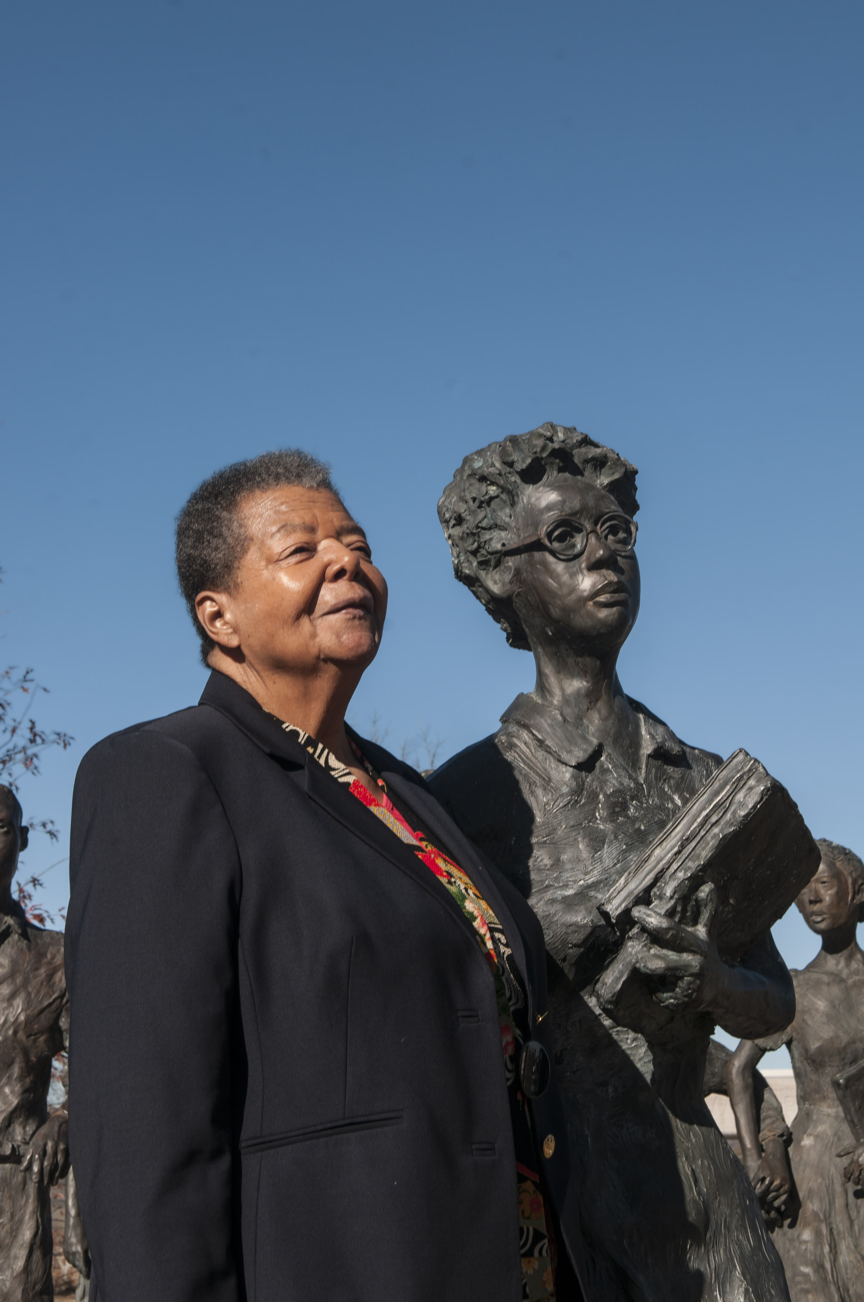 Elizabeth Eckford standing with the statue of herself